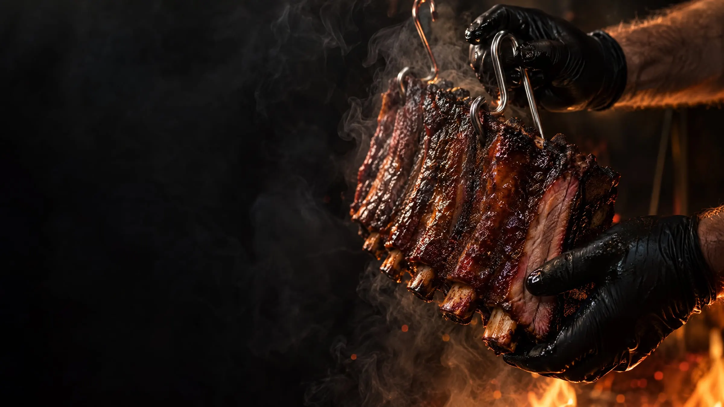 Hands in black gloves remove smoked ribs hanging from hooks